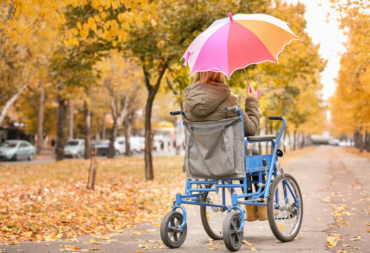 Teenage girl in wheelchair outdoors on autumn day