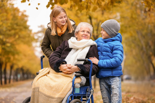 Cute children with their elderly grandmother in wheelchair outdoors on autumn day