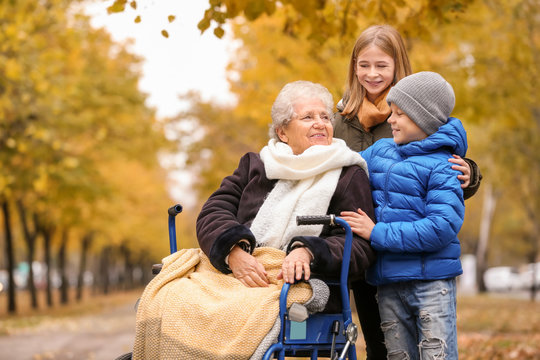 Cute children with their elderly grandmother in wheelchair outdoors on autumn day