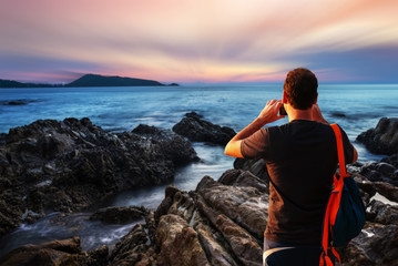 Man using smartphone shooting image on sea sunset or sunrise in twilight