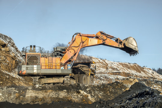 Big yellow dump truck and excavator in the coal mine, fisheye
