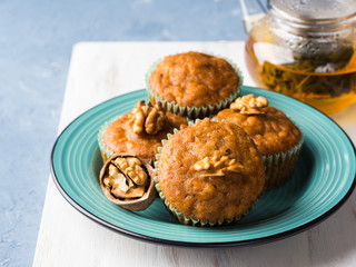 Home made Carrot spiced muffins with walnuts on green dish.