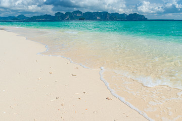 close-up of a beach with white sand and clear sea water, on the horizon of a mountain, Thailand