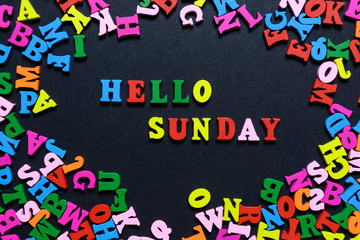 concept design - the word HELLO on SUNDAY from multi-colored wooden letters on a black background, creative idea