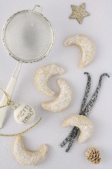 Weihnachtsplätzchen Vanillekipferl mit Vanillestangen und Puderzuckersieb