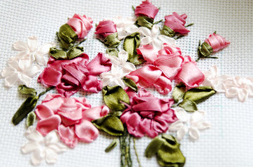 Beautiful flowers embroidered ribbon. Needlework, handicraft. Close-up, selective focus.