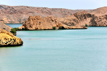 Bay with fascinating rocks at the coastline in As Sifah invites to swim, near Muscat, Oman
