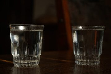 two glasses with vodka standing on a table on dark background
