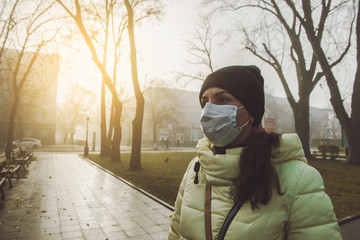 Woman suffering from sick and wearing face mask. Woman in protective mask feeling bad on the street...