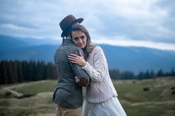 Bride and groom stand and hug on background of Carpathians mountains.