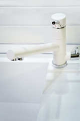 A modern white faucet in the kitchen. Style hi-tech.