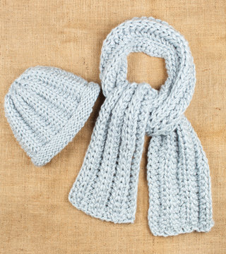 Woolen scarf and cap isolated on linen background.