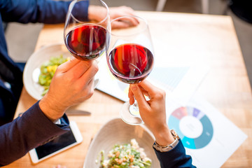 Clinking glasses with wine during the business lunch at the restaurant