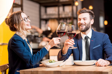 Happy business couple having a conversation during the dinner clinking glasses at the restaurant
