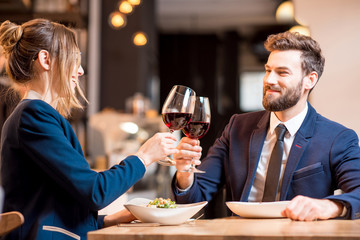 Happy business couple having a conversation during the dinner clinking glasses at the restaurant