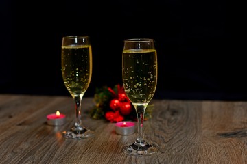 Two champagne glasses, Christmas tree, Christmas gifts and Christmas balls on black background