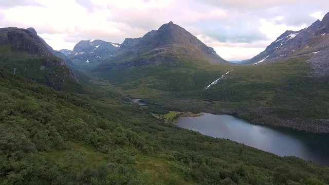 Drone flying above green forest towards a valley in the highlands