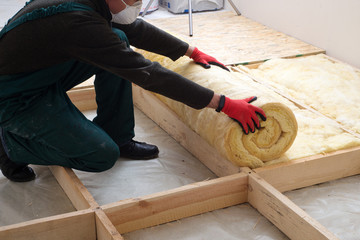 Work composed of mineral wool insulation in the floor, floor heating insulation , warm house, eco-friendly insulation, a builder at work