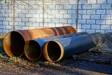 большие железные трубы лежат на улице у дороги