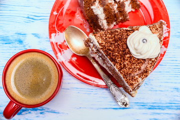 sour cream cake with cream and fresh coffee in a red mug on a light wooden background
