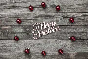 circle of red tree, evergreen, fir globes, balls, creating a circle and a Merry Christmas sign, text, on a wooden, gray background