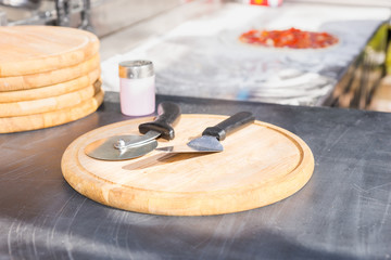 Scoop and round pizza knife on a wooden board in the kitchen