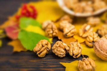 Close up of slightly scattered walnuts lying on leaves on wooden desk