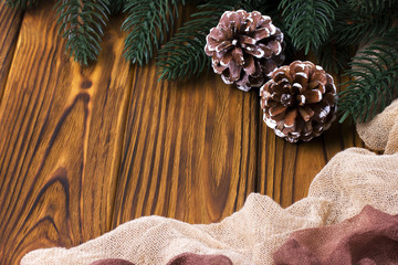 Christmas decoration with fir cones fabric brown wooden background.