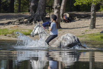 young girls play, walk and swim with horses in the water in the summer