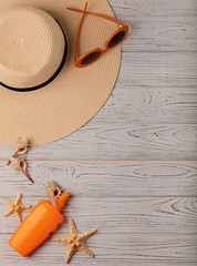 Fashion accessories - hat,  orange glasses and sunscreen on a wooden background. Selective focus.
