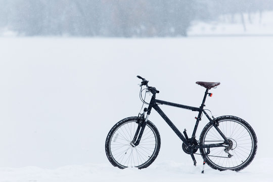 Winter season cycling. Black bicycle on the snow. Sport at any time of year concept.