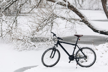 Fototapeta na wymiar Winter season cycling. Black bicycle on the snow. Sport at any time of year concept.