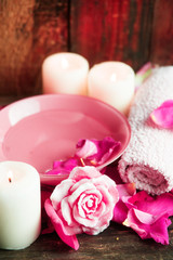 Spa settings with roses. Fresh roses and rose petals in a bowl of water and various items used in spa treatments
