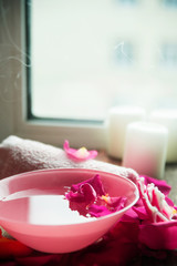 Spa settings with roses. Fresh roses and rose petals in a bowl of water and various items used in spa treatments