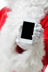 Christmas concept shot with Santa holding a white smart phone Isolated on white