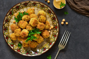 Arabian dish - falafel with sauce and cilantro on a black background.