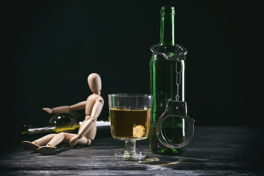 Composition of doll and alcohol on dark background. Concept of bad habits