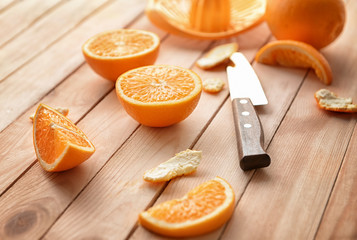 Fresh cut oranges and knife on wooden table