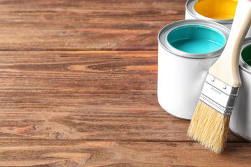 Multicolored paint in tin cans on wooden background