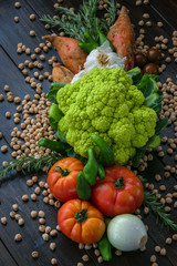 Fresh vegetables and chickpeas on wooden board. Vertical. Vegan and healthy food.
