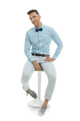 Handsome young man sitting on stool, isolated on white