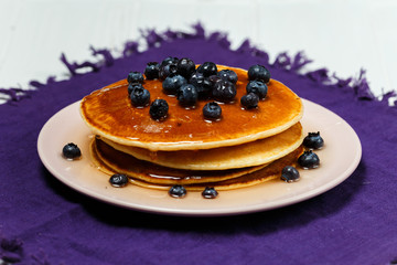 Christmas pancakes with honey and blueberries on a violet napkin