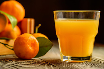 Glass of fresh juice and mandarins on table