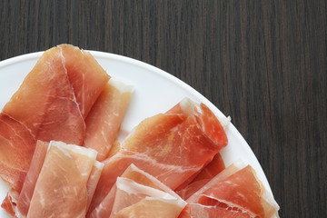 Sliced jamon (hamon) or prosciutto on a wooden background