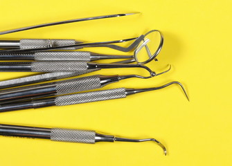 Set of metal medical equipment tools for teeth dental care isolated on yellow