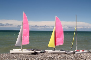 Kleine Katamarane mit pinken Segeln am Strand