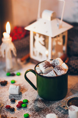 Fototapeta na wymiar A coffee mug with cocoa on the Christmas lights and candles background with marshmallows