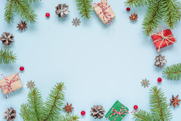 Christmas composition made of frame of fir branches, red berries, gift boxes and pine cones