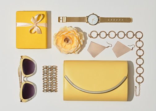 Fashion. Woman Accessories Set. Flat lay. Trendy Gold Watch, Summer Sunglasses, Glamour fashion Yellow Clutch. Flower. Luxury Stylish Spring lady. Pastel Color