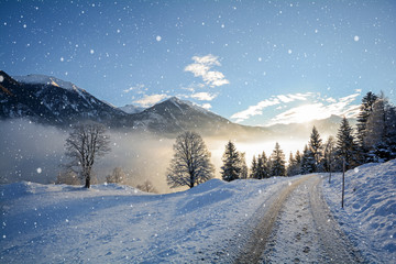 View to a icy road with snowfall and mountain range of Gasteinertal valley near Bad Gastein, Pongau...